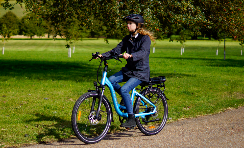 Woman with black jacker riding on a blue wisper ebike